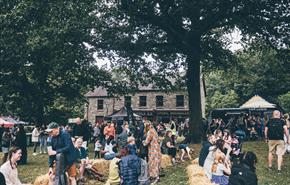 A crowd of people sitting on hay bales on Gwalia Green